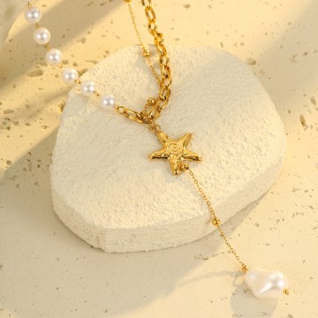 Gros plan sur l'étoile de mer dorée et la perle suspendue du collier Nolya