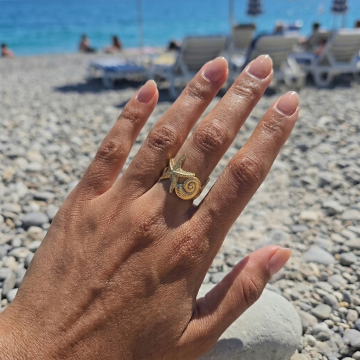 Bague étoile de mer dorée Nérée portée au doigt en bord de mer à Nice
